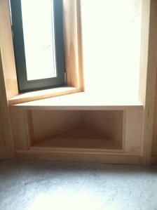 A triangular cabinet under the small bay window seat in the kitchen